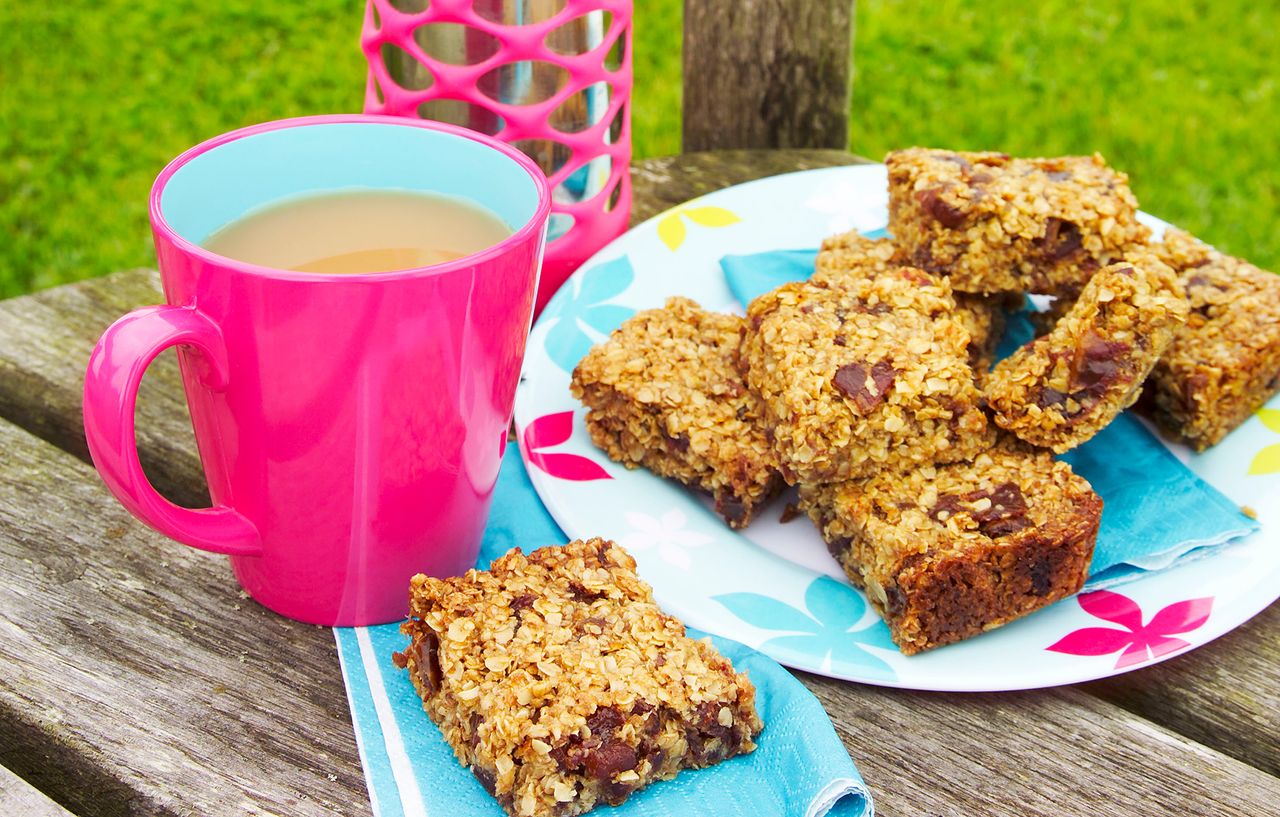 orange flapjacks with dates on a plate with a cup of tea