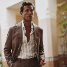 Male model wearing a brown linen suit and a stripey linen shirt sold at Moss