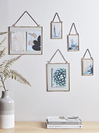 An assortment of hanging glass frames with brass finish by Cox & Cox