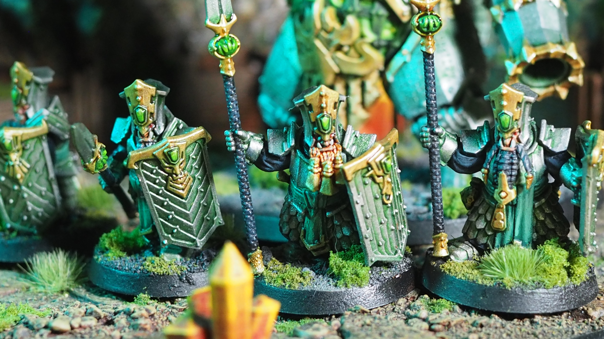 A lineup of Helsmiths of Hashut warriors armed with spears in a rocky environment, with a larger model looming behind them