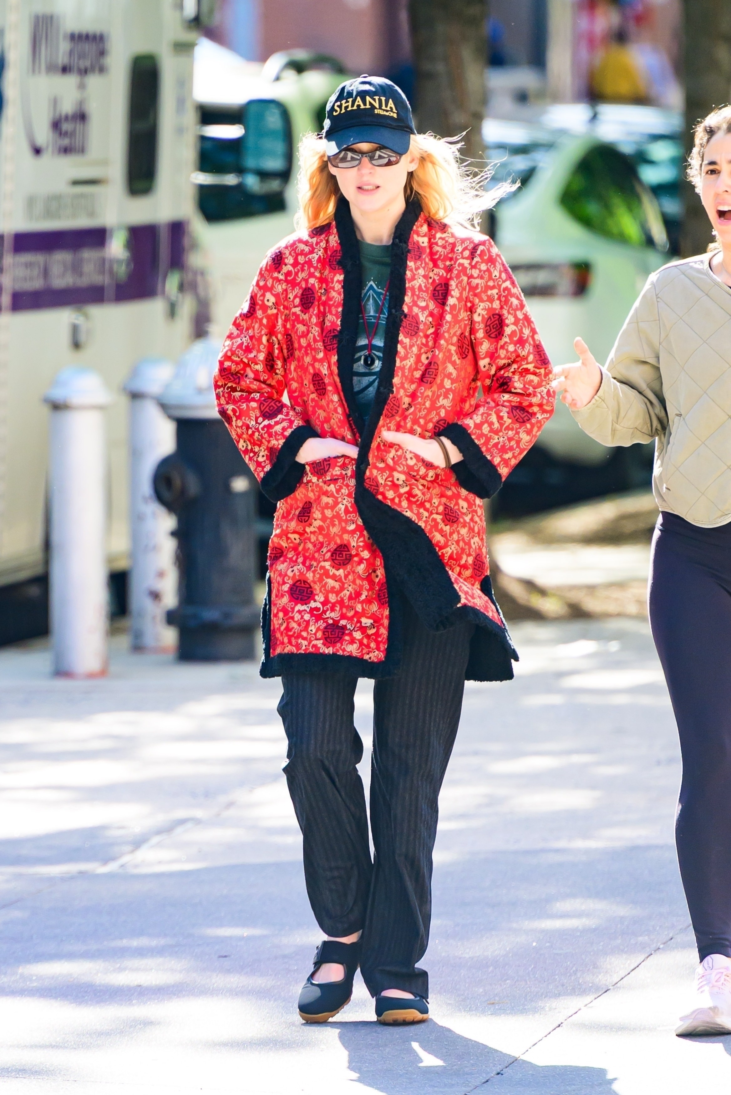 Jennifer Lawrence wears a red jacket, baseball cap, black pants, and ballet sneakers.