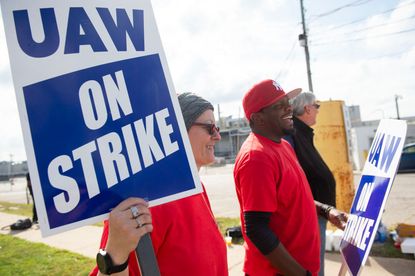 UAW union members striking with blue and white signs