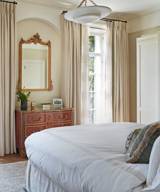bedroom with curtains and antique chest and mirror and pendant light