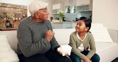 a grandfather and his granddaughter holding a piggy bank talking about finances