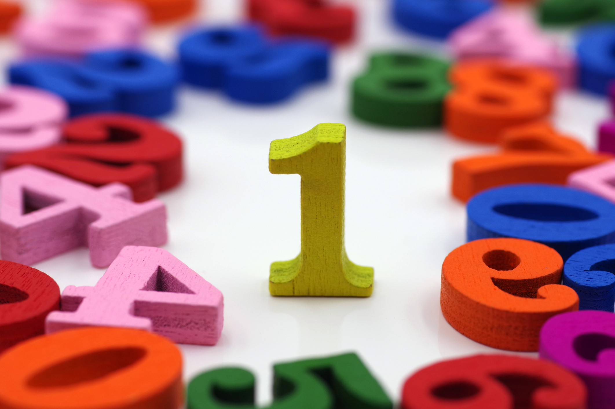 Colorful wooden numbers on a white background with focus on the number one