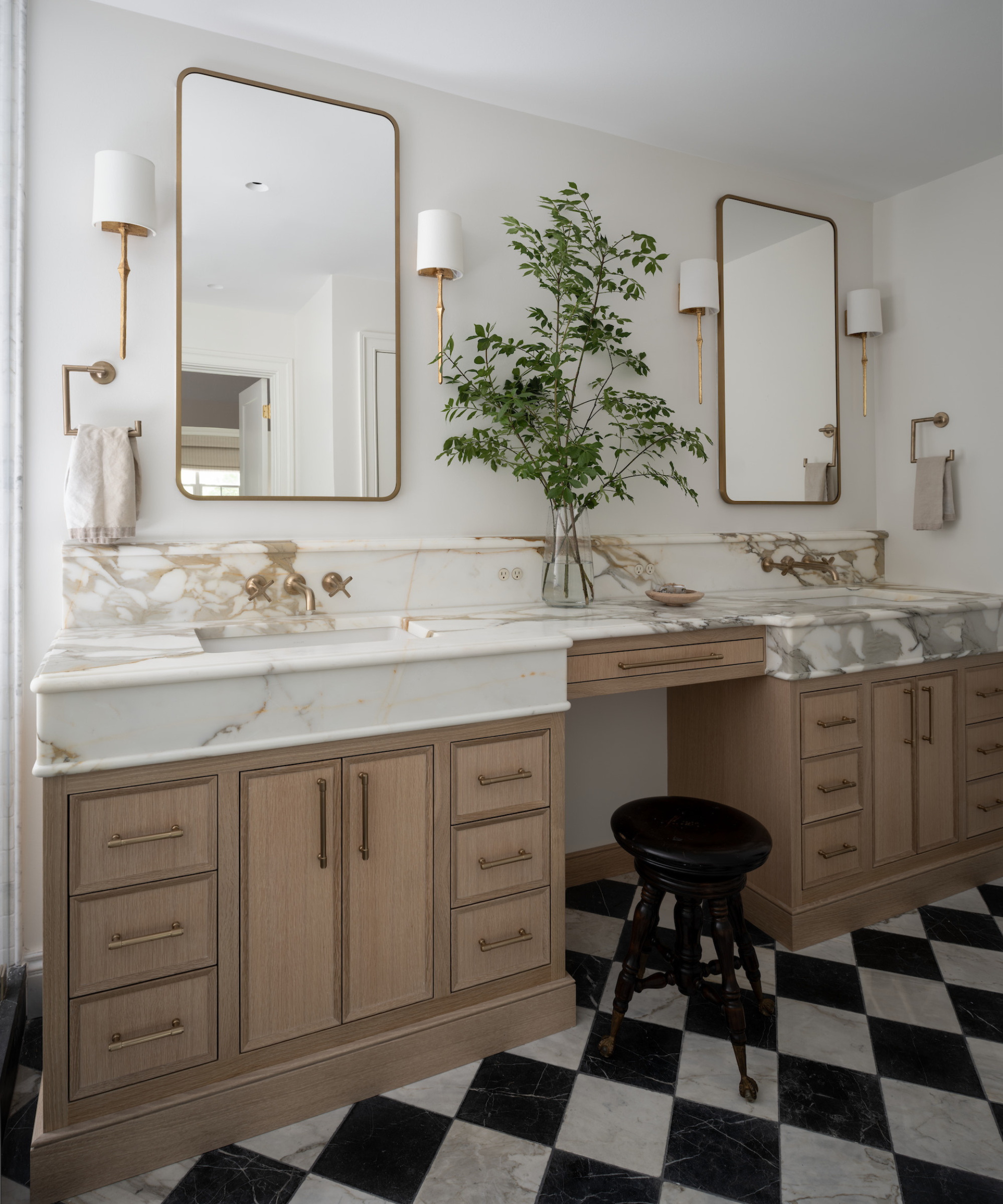 a bathroom with a double vanity, marble countertops, and a large plant in the middle