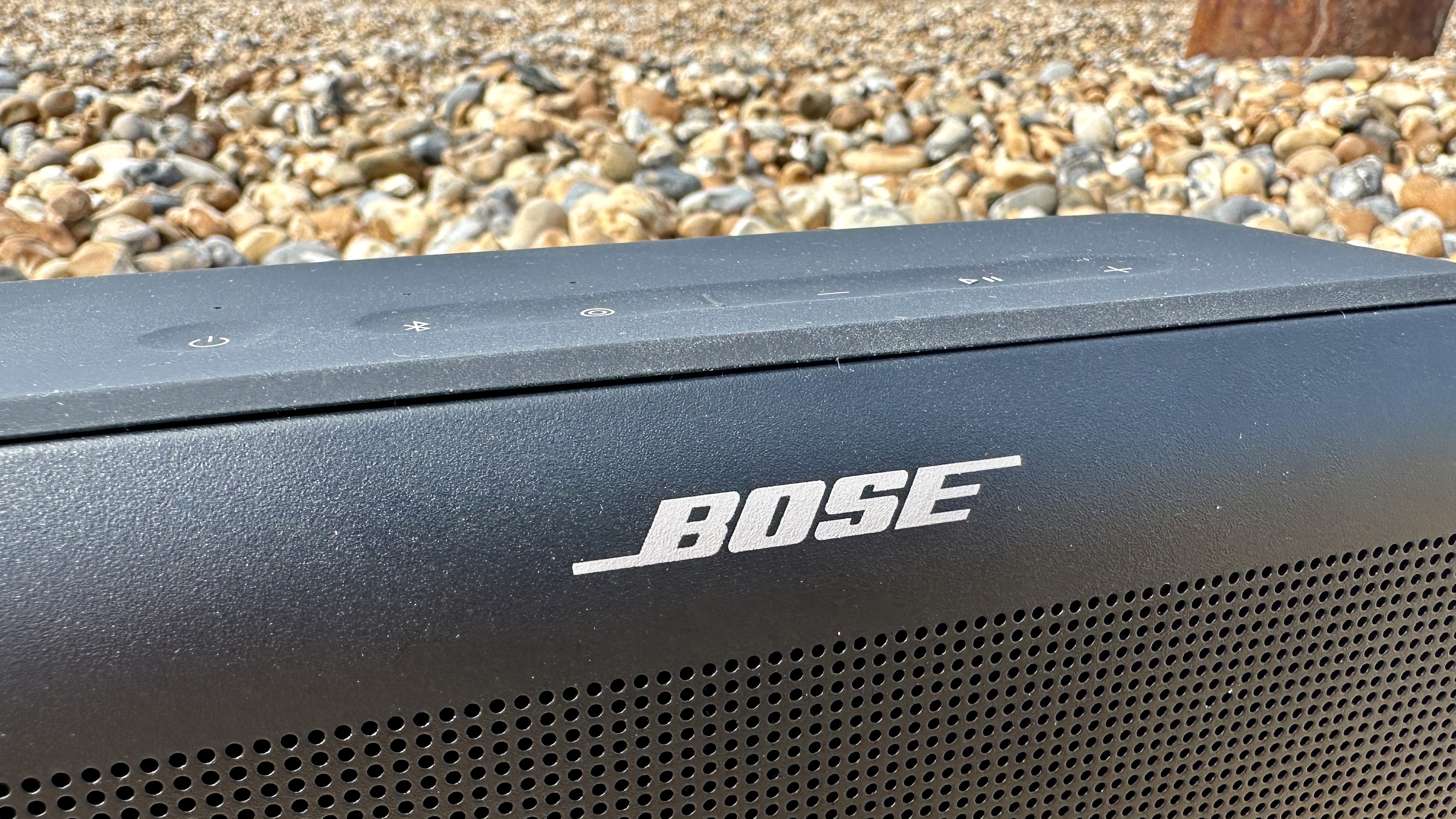 Bose SoundLink Plus on Brighton Beach pebbles, with the old pier in the background