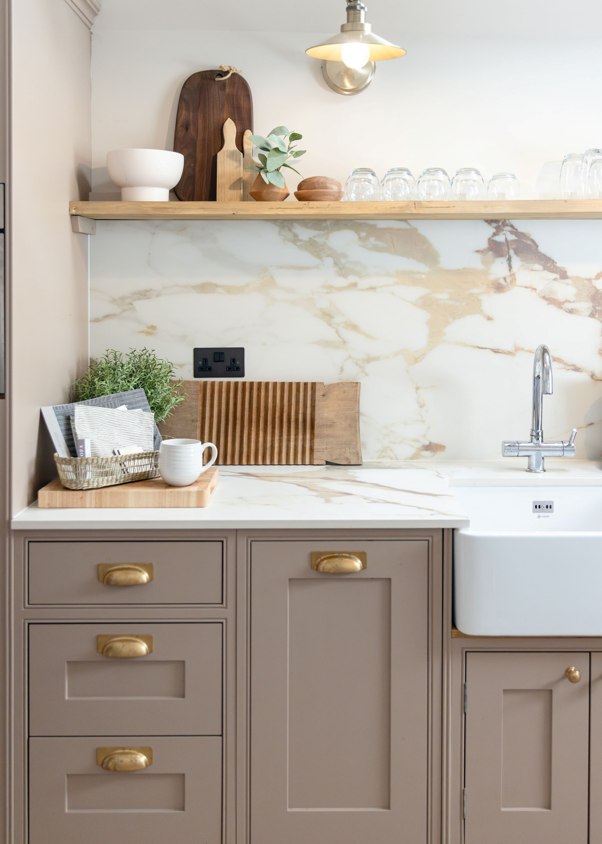 griege/ cashmere kitchen design with brass handles and a marble splash back