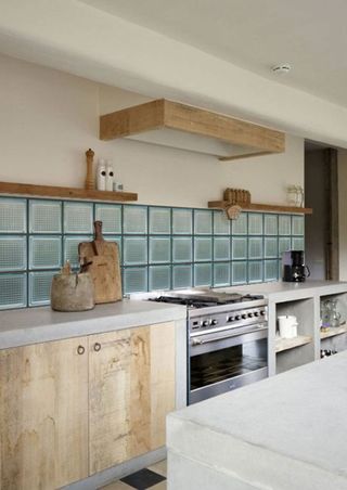 a kitchen with stripped back wood cabinetry and square glass bricks as backsplash tiling