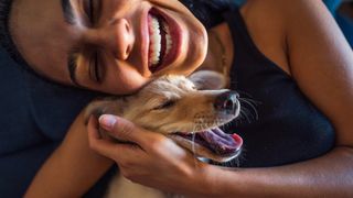 Woman laughing and cuddling dog