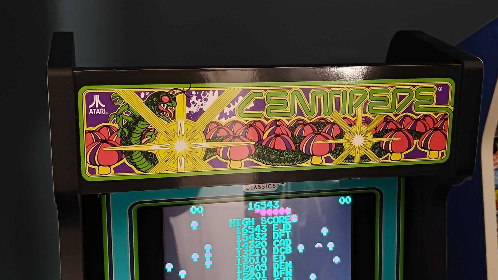 Close up of Arcade Classics Cenitpede machine wood marquee