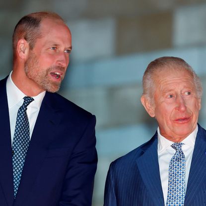 King Charles and Prince William talking to each other wearing blue suits