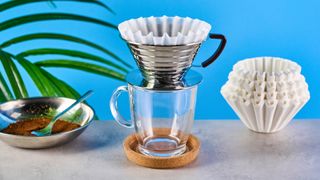 kalita wave stainless steel pour-over coffee dripper photographed against a blue background with kalita filters