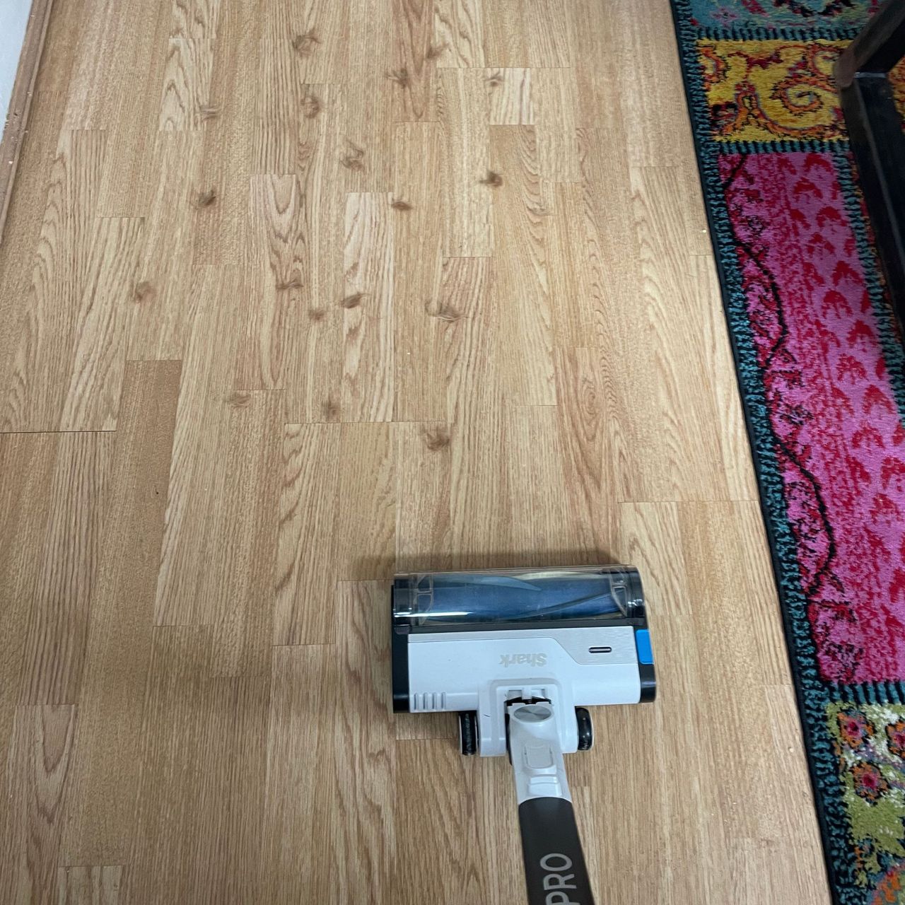 Using the Shark PowerPro Pet Cordless Stick Vacuum on laminate floor sprinkled with pet hair