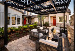 Covered patio space with dark wicker chair table set over medium format tiles