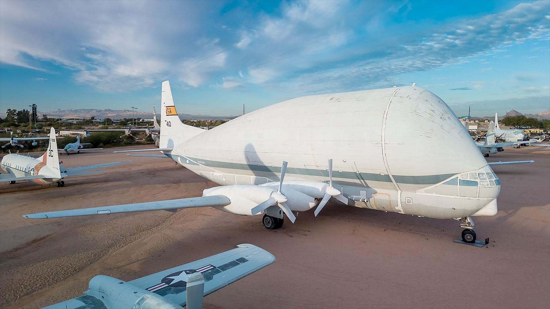 a whie oversized cargo aircraft is seen on outdoor display at a museum