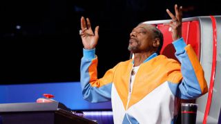 Snoop Dogg closes his eyes with his arms raised on The Voice Season 26.