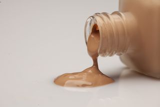 a bottle of foundation on a table with product spilling out