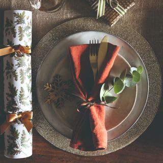 A Christmas table setting with a place setting, a napkin and a cracker