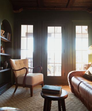 dark green painted snug small living room with wooden panelled ceiling and vintage furniture