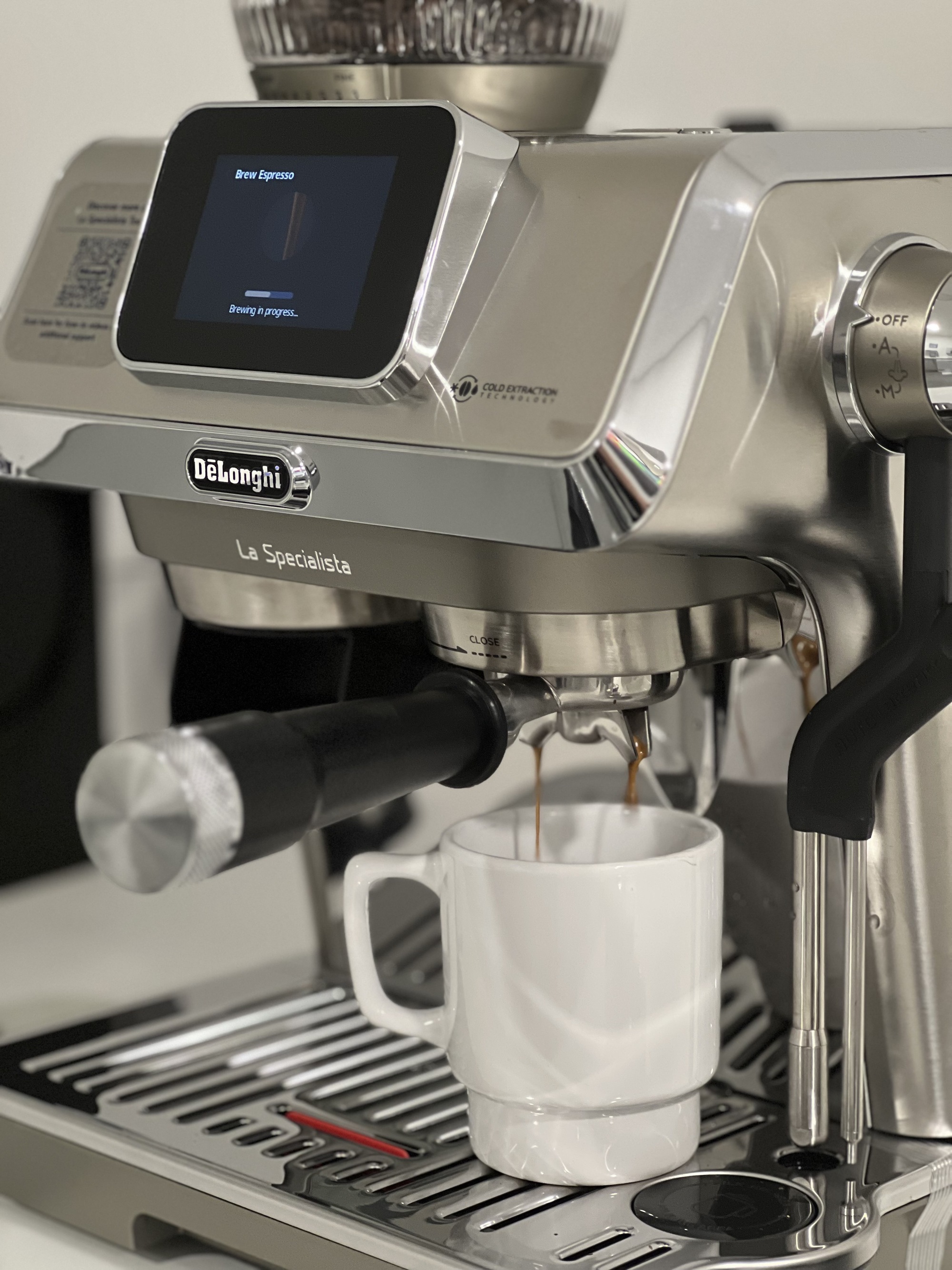Close up image of the De'Longhi Specialista Touch brewing a shot of espresso into a white coffee mug.