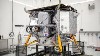 a silver spacecraft with gold legs sits in a white room.