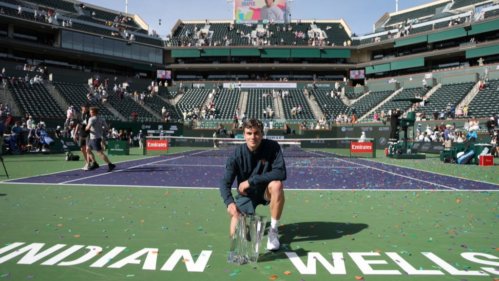 Jack Draper kneels with the trophy on court after winning Indian Wells 2025.