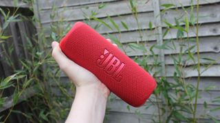 Bluetooth-høyttaleren JBL Flip 6 i rødt, som holdes i en hånd.