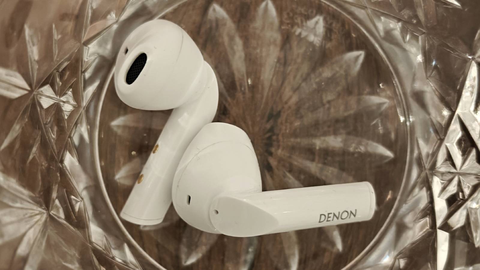 The Denon AH-C500W buds inside a glass.