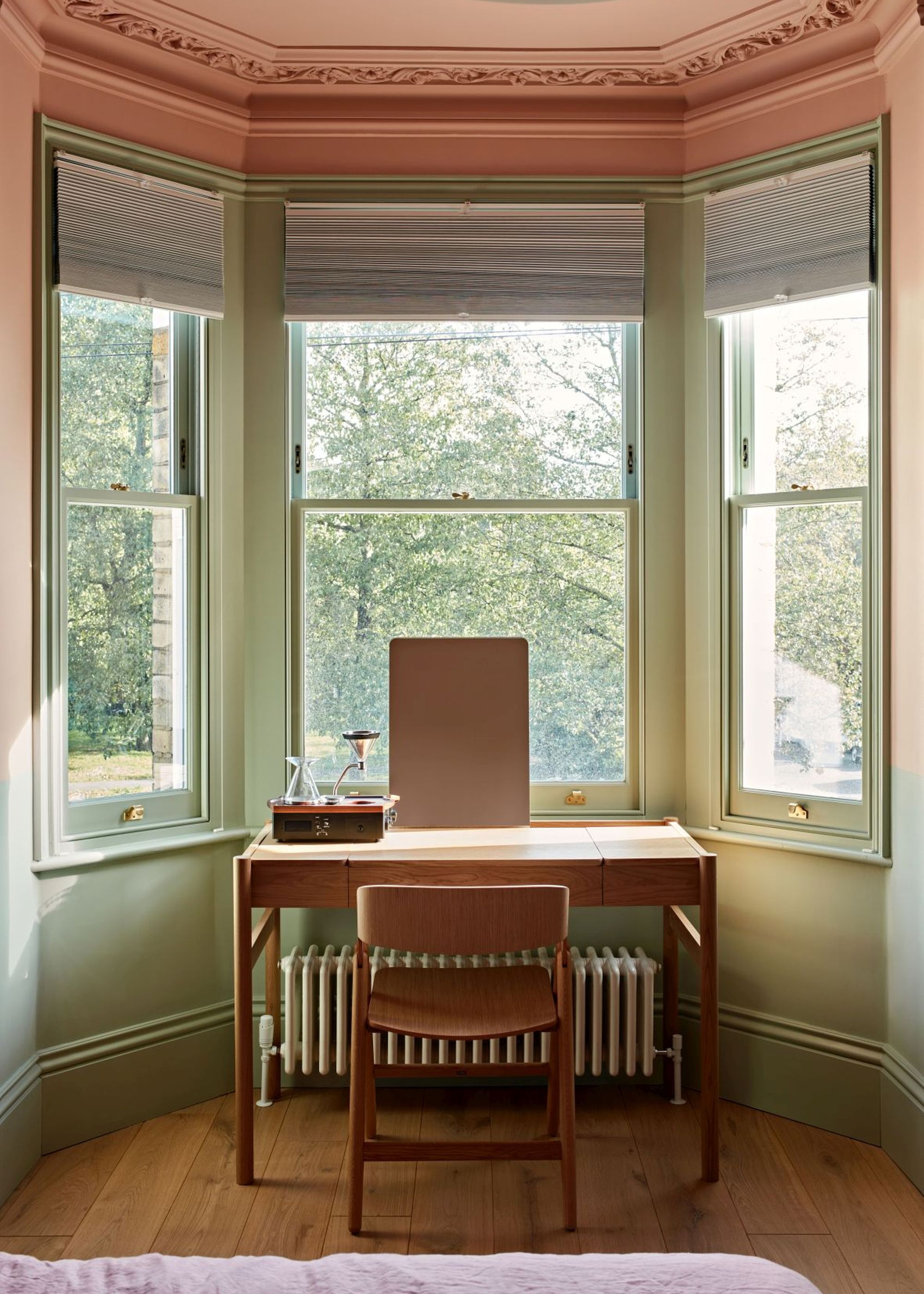 bay window with woodwork painted sage green, pink ceiling with architectural details
