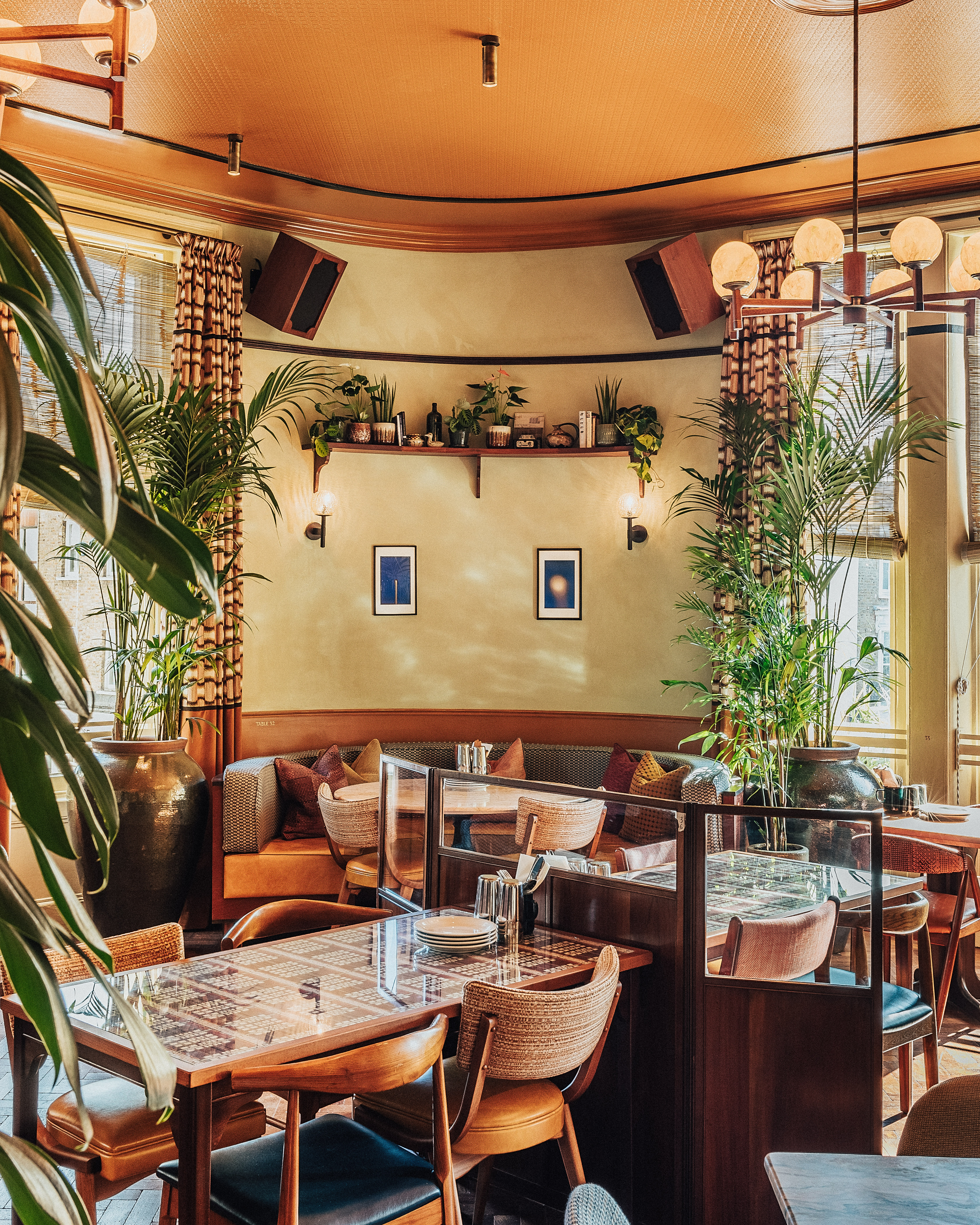 An old public house has been restored into a Bombay-inspired restaurant and bar with rooms, adorned with original artworks, vintage furnishings, and thriving plants and dressed in earthy tones.