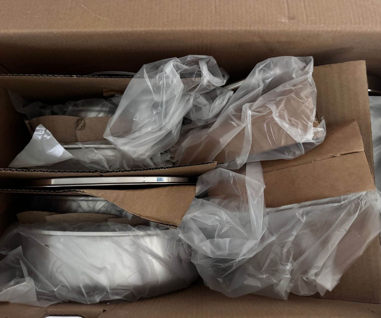 The inside of the Greenpan Thermobond pan box, with the pans packed in plastic bags and divided by carboard.