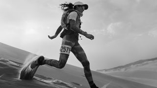 A woman runs through a desert, wearing the Apple Watch Ultra.