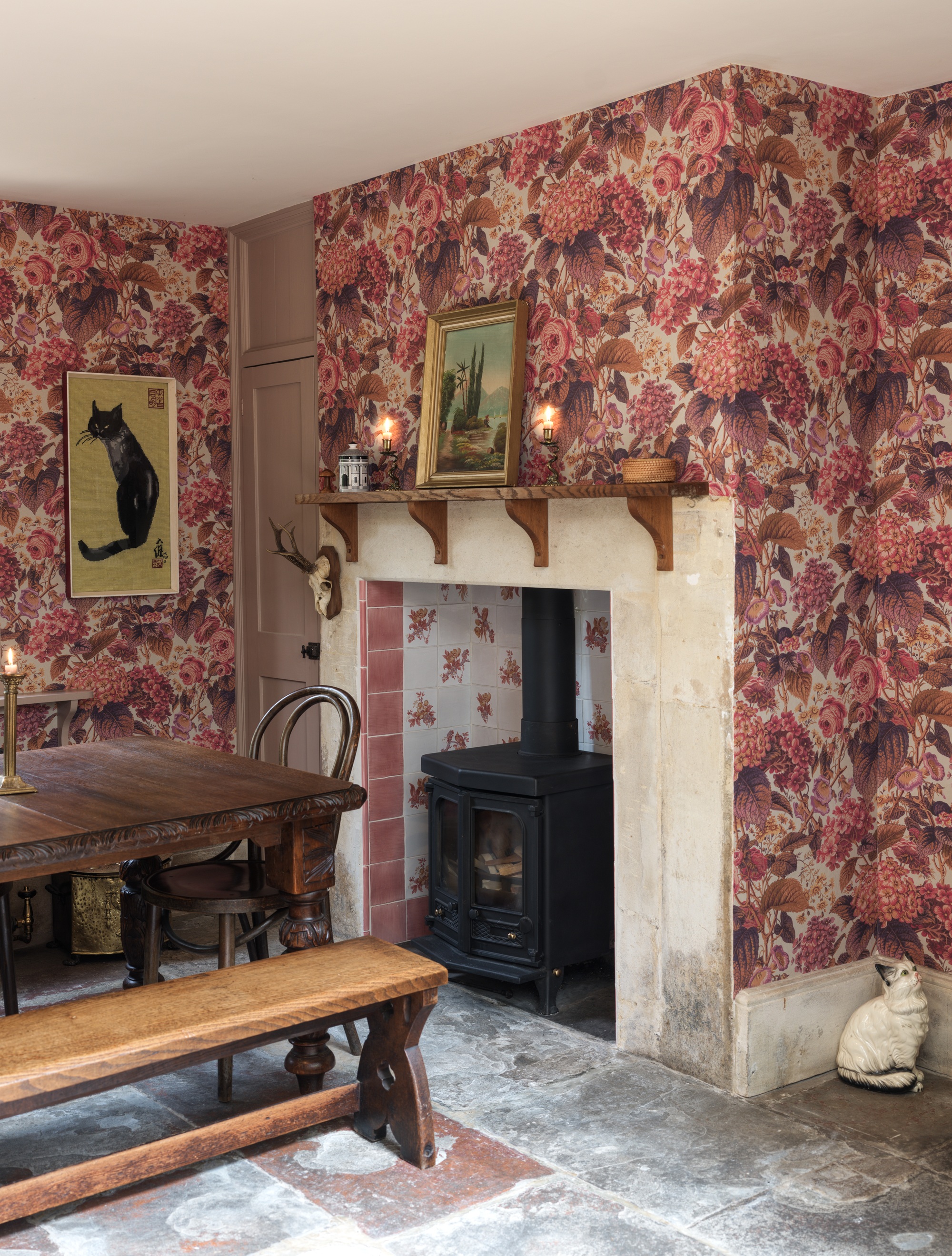 a dining room with patterned pink floral wallpaper and a stove