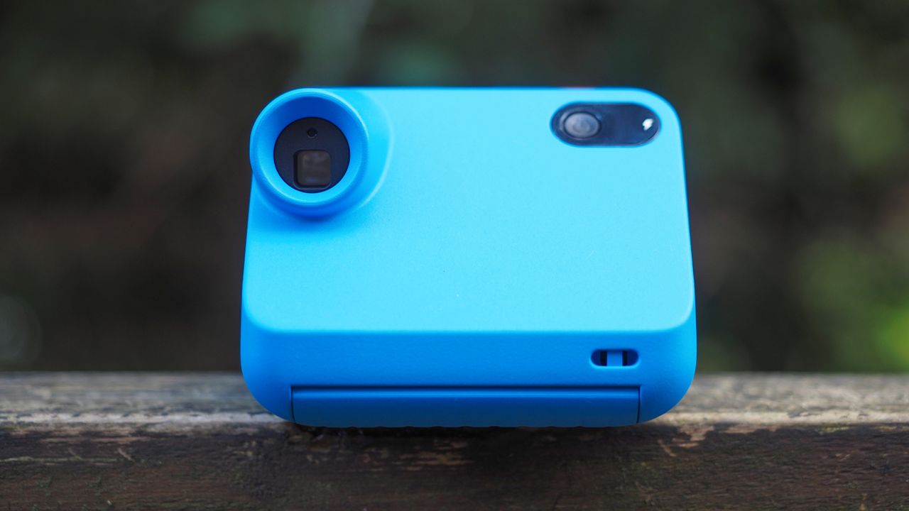 Blue Polaroid Go Gen 2 camera, on a wooden surface in a woodland setting