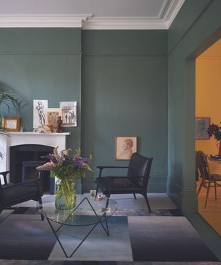 Living room painted in Green Smoke by Farrow & Ball with white fire place and adjoining yellow room