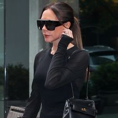 Victoria Beckham ended her colorful streak in an all-black skirt set and a rare Hermès Kelly bag