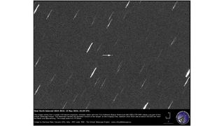 telescope photo of the sky, showing white streaks that represent stars and a small white dot that's an asteroid