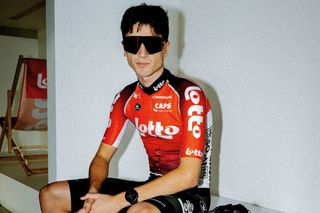 A Lotto rider in his 2025 kit, an almost fully red jersey with black accents