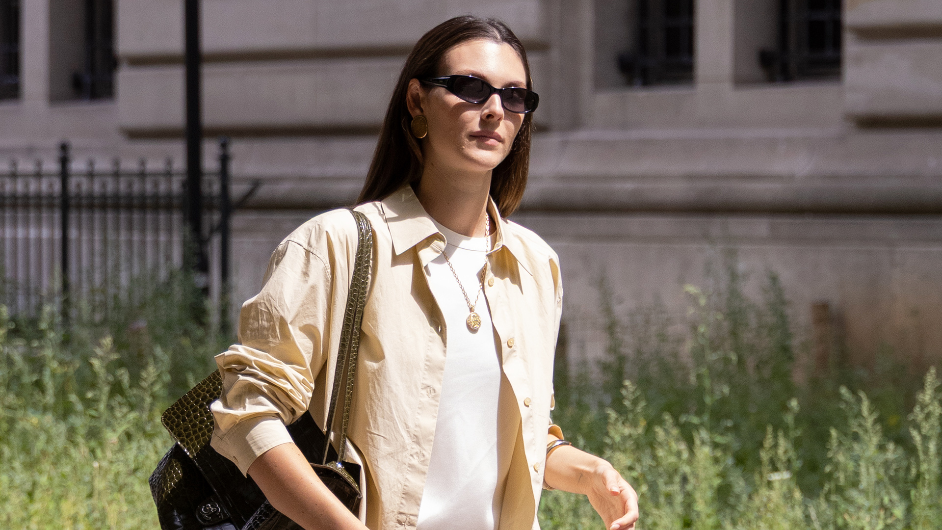 Vittoria Ceretti in Paris wearing a yellow button-down over a white T-shirt with white striped pull-on shorts and brown suede slipper mules.
