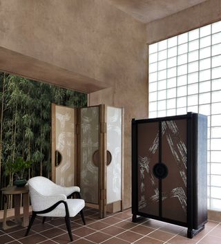 A living room space with furniture by Andre Fu, facing a traditional japanese zen garden with bamboo plants