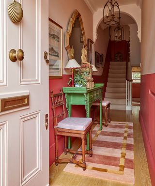 hallway with pink striped runner and pink and red painted walls and bright green console