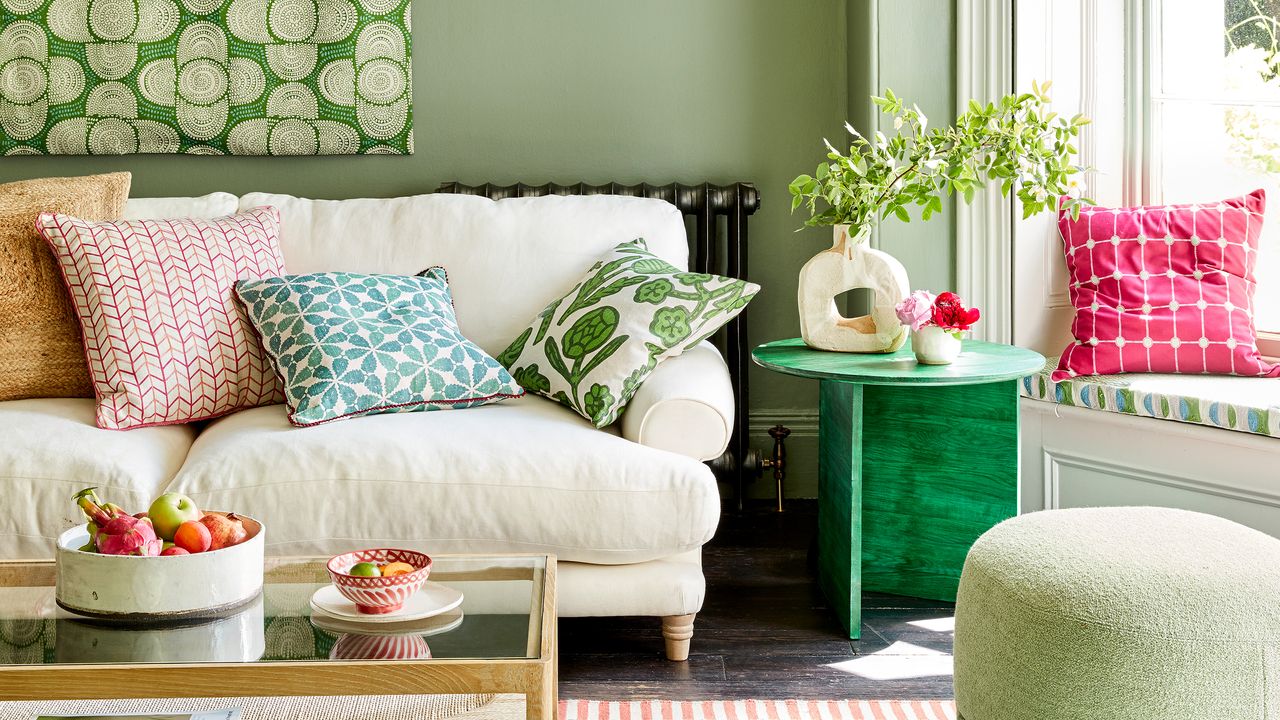 Green living room with textile artwork above cream sofa