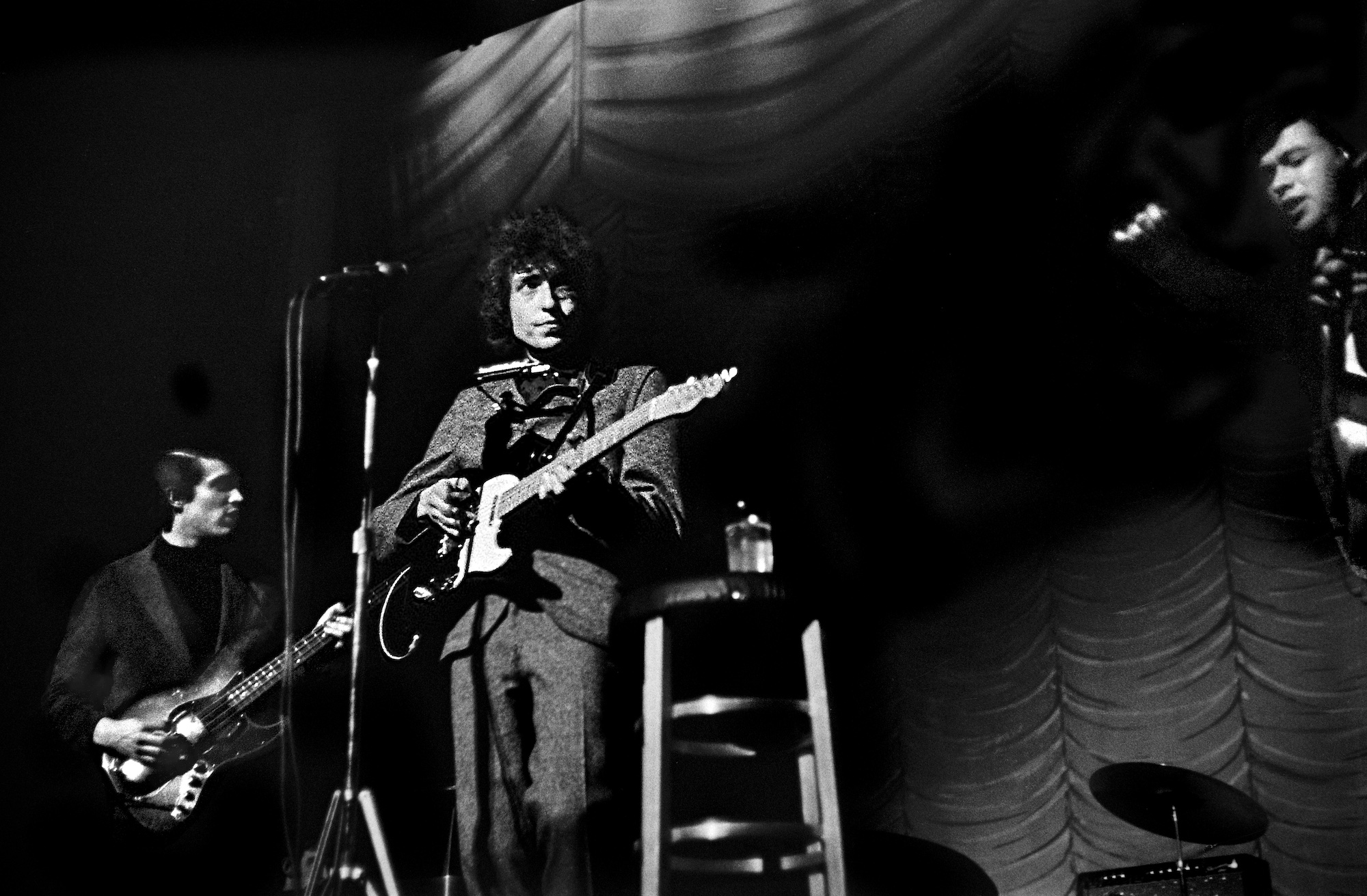 Bob Dylan performs onstage with Rick Danko (left) and Robbie Robertson (far right) at the Academy of Music in Philadelphia, Pennsylvania on February 24, 1966