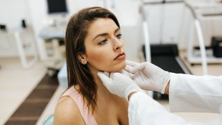 Doctor examines young woman's thyroid