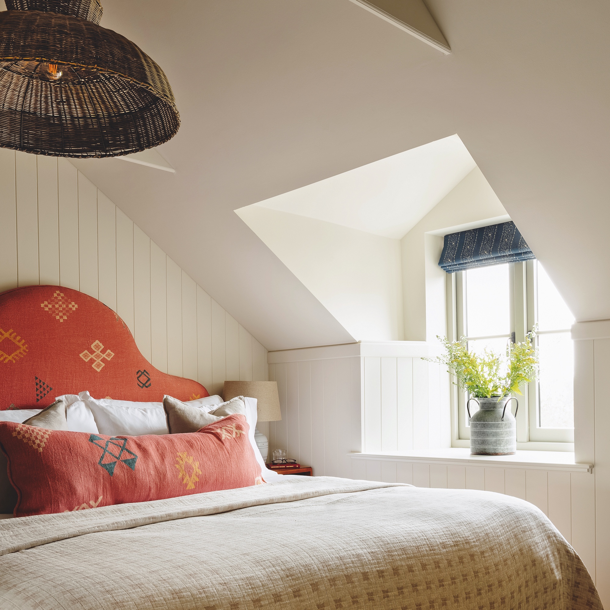 eaves bedroom with tongue and groove panel walls painted white and upholstered orange headboard