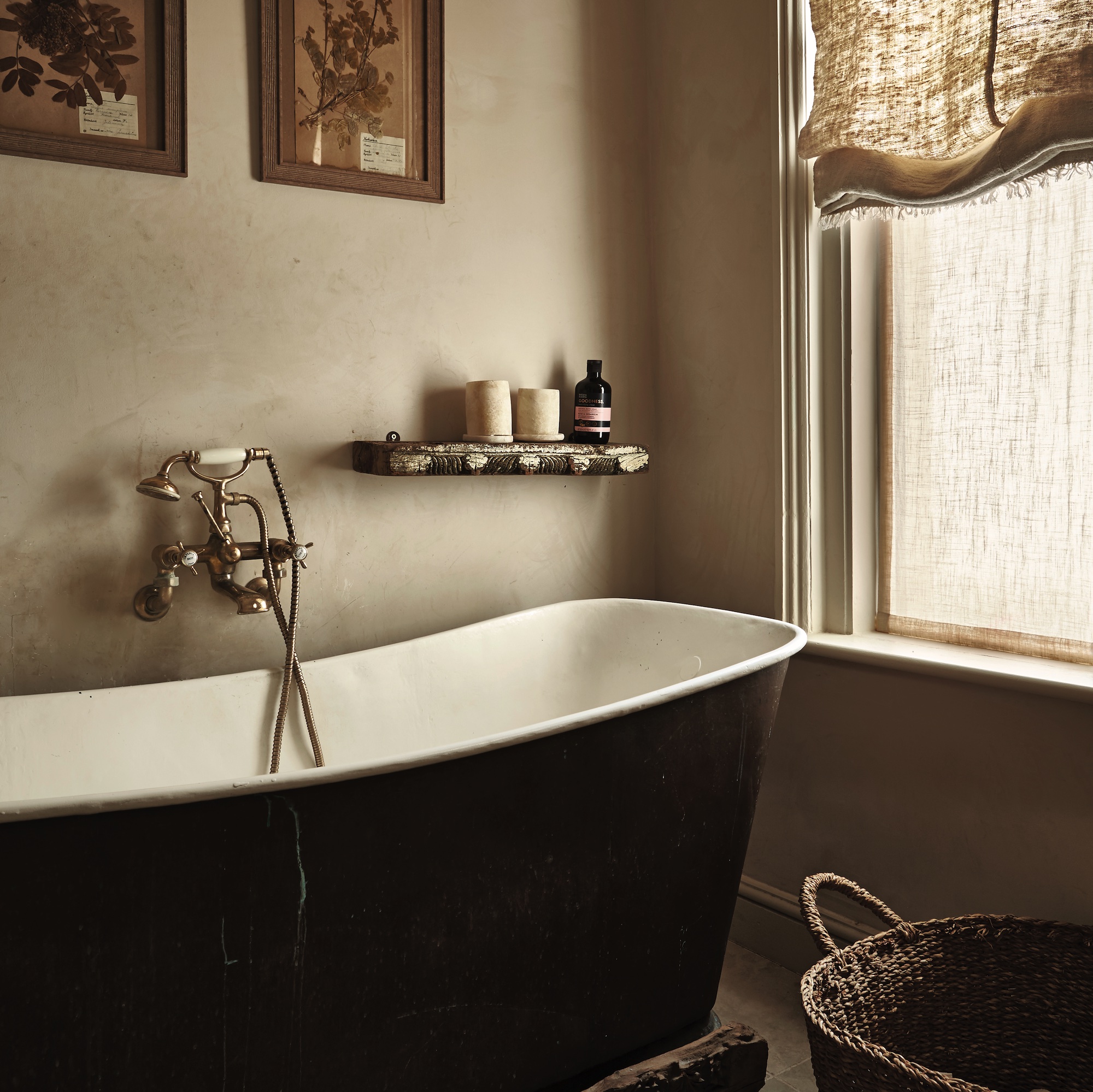 bathroom with limewash walls and large black antique slipper bath and wallmounted taps