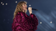 Taylor Swift performing on stage in a glittery pink coat