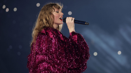 Taylor Swift performing on stage in a glittery pink coat