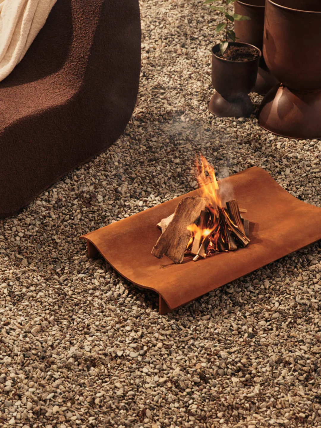 A rust-colored outdoor fire pit tray from Ferm Living